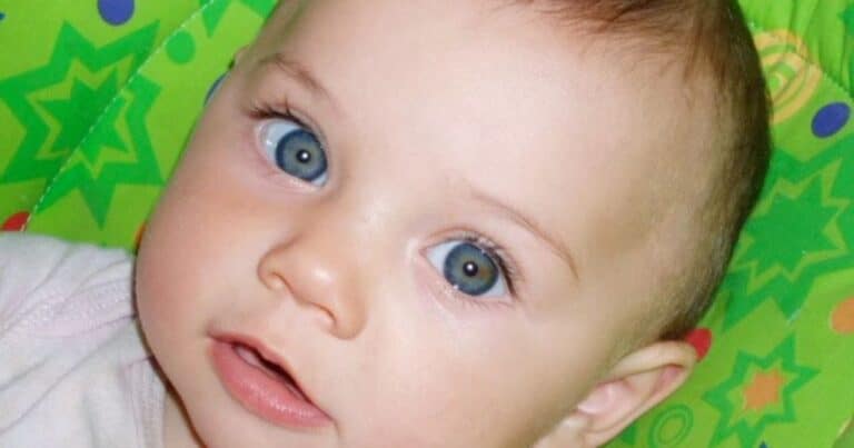 Development of oral language begins at birth and before. Close up of a baby's face on a green background with colorful shapes.