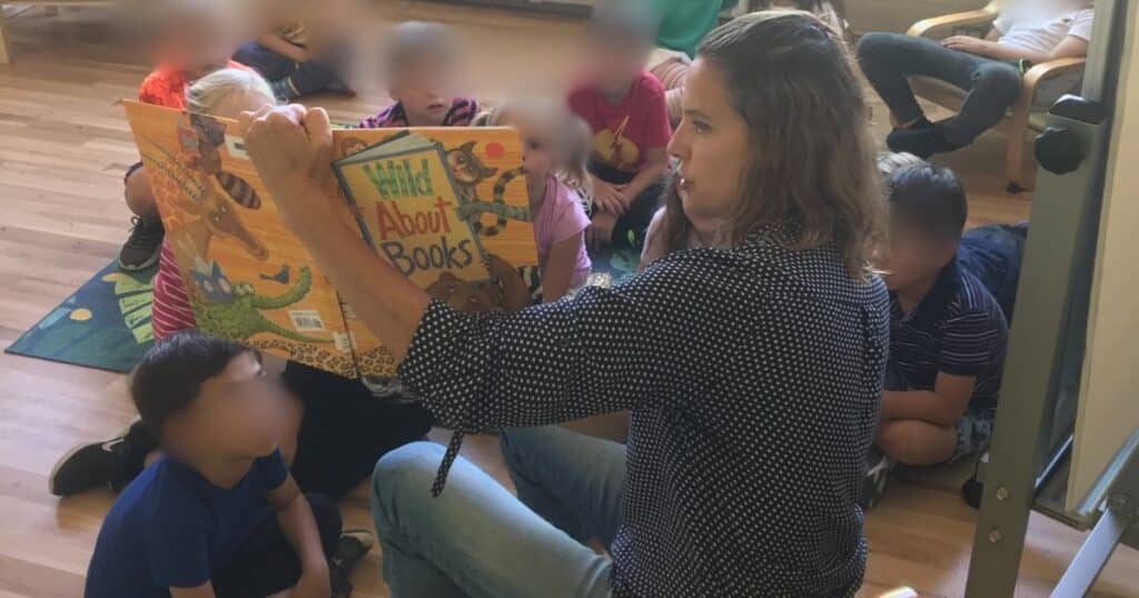 Teacher reading a book aloud to a group of children. Reading aloud is an excellent way to promote listening skills.