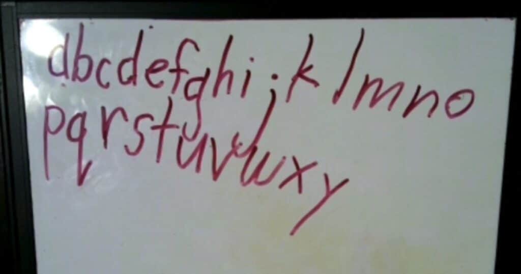 Alphabet written in red on a whiteboard.
